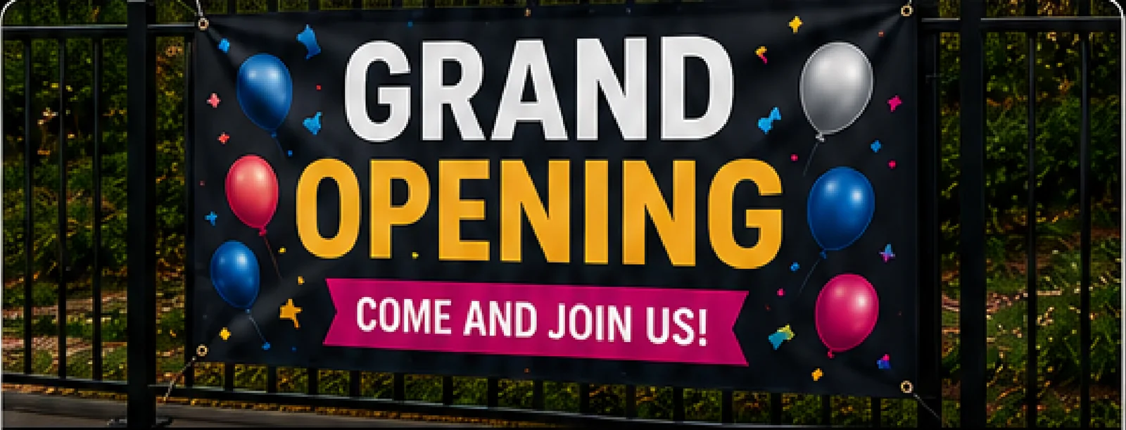Large outdoor Grand Opening banner with balloons, mounted on a fence.